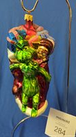 Front view of the Radko The Grinch glass Christmas ornament on a stand with Max and the Who child visible