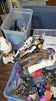 Top view showing various action figures piled in a plastic container, including Star Wars characters and other figures.