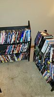 Photo showing two black wooden DVD holders loaded with various TV series DVD and Blu-ray sets arranged on shelves.