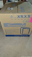 Box of Kenmore compact refrigerator with product details and logo visible.