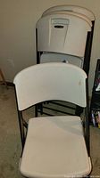 Four white Lifetime folding chairs stacked together showing the backs with Lifetime logo and black metal frames.