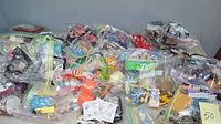Wide view showing many McDonald's Happy Meal toys sealed in plastic bags on a table, with multiple colorful figures and packaging visible.