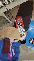 Photo showing skateboard, wooden board, pink dumbbells, blue kneeling board