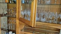 Wooden cabinet with multiple shelves filled with Waterford crystal and cut glass stemware and glassware including goblets and glasses.