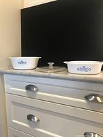 Two Corningware casserole dishes on countertop, showing classic blue flower design