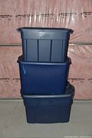 Three stacked large Rubbermaid storage bins in dark gray and blue colors, showing the size and shape
