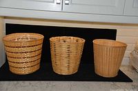 Photo showing three round wicker baskets of varying sizes arranged side by side on black fabric, highlighting the weave patterns and nesting ability.