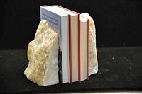 Book ends positioned with three books held between them on black background, showing texture and color.