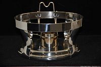 Stainless steel circular frame with a central container for heating fuel or water, polished finish