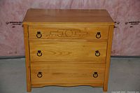 Front view of the 1920s wooden dresser with three drawers and ring pull handles, showing decorative carved detail on the top drawer.
