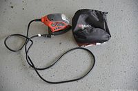 Photo of the Black & Decker finishing sander, power cord, zippered storage pouch, and sanding paper sheets laid out.