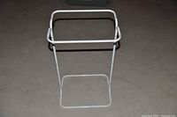 White metal tubular garden garbage bag stand with rectangular frame on top and base for support.