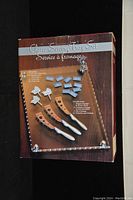 Original packaging box showing the set name and contents including the tray, spreaders, butter knife, and small labels.