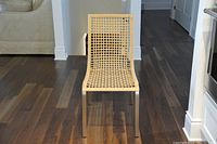 Front view of the light tan faux wicker IKEA chair with metal legs showing the open grid pattern seating and backrest.