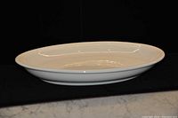 Side profile view of the white ceramic platter showing oval shape and raised edges.