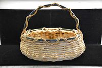 Photo showing a large oblong wicker basket with twisted handle and green trim woven into the rim and handle.