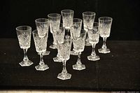 Photo of 12 Bohemian cut crystal liquor glasses arranged in rows showing their shape, size, and intricate cut pattern.