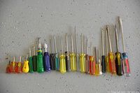 Photo of a set of 22 assorted screwdrivers arranged in a row showing various handle colors and shaft lengths and types.
