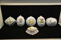 Set of six Franklin Mint ceramic moulds displayed on a black background, showing various fanciful designs including birds, flowers, fruits, and a rabbit. One smaller mould features gold trim.