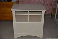 White dresser front view showing four top cubby storage compartments and a closed large file drawer below.