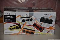 Front side of the original packaging showing the Yamaha TSX-112 desktop audio system in multiple color options including black, white, yellow, orange, and red.