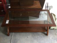 Front view of the wood coffee table showing the glass top and lower shelf