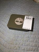 Closed metal tin with tree logo on lid and lot label attached.
