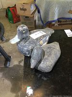 Photo showing two vintage wooden duck decoys with worn paint and signs of aging, placed on a black surface.