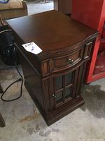 Front and side view of dark stained wood end table with drawer and cabinet door with glass panels