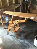 Side view of solid oak combination ironing board with step stool and chair functions in a raised ironing board position.