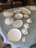 Overview of the full set showing all items including platters, bowls, cups, saucers, and gravy boat arranged on a blue quilted surface