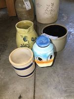 All items grouped showing stoneware crocks, yellow pitcher floral design, and Donald Duck biscuit jar.
