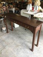 Front angle view of solid wood sofa/hall table showing three drawers with brass handles and surface wear.