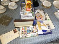 Stamp box with envelopes labeled 'CANADA', loose stamps, and a stamp catalog inside a blue shoe box.
