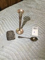 Photo of the full set showing the bud vase, teaspoon, and cigarette case on a quilted surface.