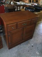 Front view showing the two cabinet doors and drawer with metal hardware and minor wear on surface.
