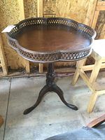 Side view showing the kidney-shaped tabletop with raised pierced gallery and central pedestal base