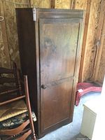 Front view of the small vintage wooden wardrobe showing door, handle, and overall structure.