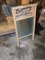 Front view of vintage wooden washboard showing glass insert and printed text.