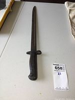 Full view of the WW1 Wilkinson bayonet showing blade and handle on white surface.