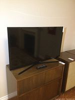 Front view of a 40-inch Samsung flat screen TV on a wooden cabinet with remote placed in front