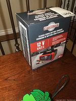 Motomaster battery charger box showing brand and key features on the front panel.