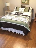 Bed fully set up with bedding, pillows, and lamp on side table