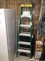 Full front view of 6 ft fiberglass step ladder showing green frame and yellow top cap.