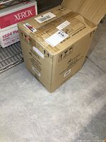 Closed cardboard box with shipping labels and Keurig branding, containing the coffee maker.