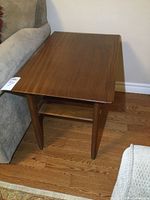 Front corner view of end table showing tabletop, tapered leg, and partial lower shelf