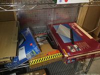 Shelf view showing various boxed items including the paper cutter and Pelican case along with router and keyboard boxes.