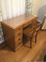 Solid maple desk and matching wood chair shown against a window with curtains. Glass topper visible on desk surface.
