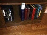 Shelving unit with several binders and stamp books, including multiple 'First Day Cover' binders in different colors and various books on the right side.