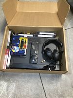 Box containing the Sony VCR player, remote, Apex headphones, VHS to DVD converter, and blank VHS tapes.